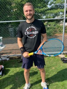 man holding tennis racket and smiling